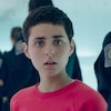 Une jeune femme (Nahéma Ricci), l'air interloqué, entourée d'agents et d'agentes des services frontaliers, de dos.