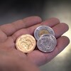 Une main tenant des pièces de monnaie dorées et argentées.