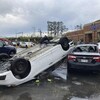 Une voiture renversé sur une autre voiture dans un stationnement