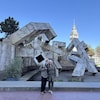 L'artiste Armand Vaillancourt et sa conjointe Joanne Beaulieu, devant la Fontaine Vaillancourt, dans un parc. 