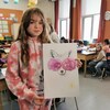 Une jeune élève présente son oeuvre dans une classe.