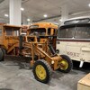 D'anciens véhicules agricoles ou de transport collectif sont rassemblés dans un entrepôt.