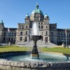 Une fontaine d'eau est devant un bâtiment en pierres.