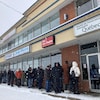 Une cinquantaine de personnes attendent dans la neige devant une succursale de la Société de l’assurance automobile du Québec.