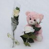 Une rose blanche a été planté dans le neige et un ourson rose a été placé à côté. 