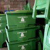 Des bacs de plastique verts empilés dans ce qui semble être un entrepôt.