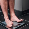 Un homme se tient sur une balance.