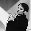 Dans un studio de télévision, la chanteuse française Barbara interprète une chanson en tenant un micro à fil à la main.