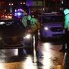Des policiers interceptant des voitures, la nuit.