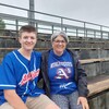 Un adolescent assis avec sa mère dans des estrades de baseball.