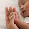 Un bébé qui dort en tenant la main de sa mère.