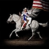 La chanteuse est assise à l'envers sur un cheval avec un drapeau américain. 
