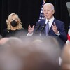 Joe Biden parle à des gens, avec sa femme, qui porte un masque, en arrière-plan 