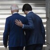 Joe Biden et Justin Trudeau de dos, à côté d'un drapeau du Canada.