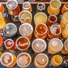 29 verres pleins de bière artisanale posés sur une table et photographiés par en haut.