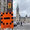 Un panneau de circulation indique en anglais et en français que la route est fermée devant le parlement à Ottawa.