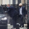 Boris Johnson, masqué, s'apprête à entrer dans une voiture. 