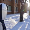 Une borne de recharge pour voiture électrique dans la neige en avant d'une résidence.