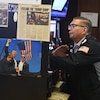 Un négociateur à la bourse regarde son écran, alors que sur un mur est affichée une photo de Donald Trump, brandissant le poing, le jour où il avait été blessé à l'oreille dans une attaque.
