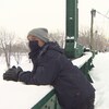 Bradley James est appuyé sur la balustrade d'un pont, en hiver. 