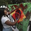 Une manifestante met de la peinture rouge sur le drapeau brésilien.