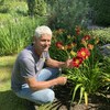Le directeur général du Jardin Scullion, Brian Scullion, se trouve à proximité d'un massif de fleurs. Il est souriant.