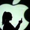 Une silhouette de femme consultant son téléphone en ombre chinoise dans le logo d'Apple.