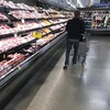Un homme marche sans s'arrêter devant la section des viandes, à l'épicerie.