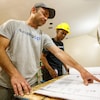 A man points at construction plans to a woman.