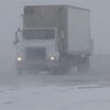 Un camion circule sur une route enneigée.