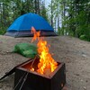 Une tente et un feu de camp sur un terrain de camping.