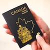Des mains tiennent un nouveau passeport canadien.