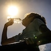 Une personne boit de l'eau lors d'une journée ensoleillée.