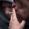Plan rapproché d'un homme fumant un joint, vu de profil.