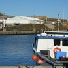 Un bateau de pêche avec l'usine de transformation de la coopérative à l'arrière-plan.