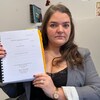 Une personne montre un dossier à la caméra.