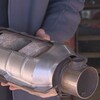 Un homme tient un convertisseur catalytique dans ses mains.
