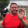Un homme tient dans sa main gauche une cerise alors qu'il se tient dans la rue.