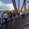 Des gens se tiennent par la main le long d'un pont.