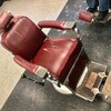 La « chaise célèbre » du salon de barbier Victoria Barber Shop, faite en cuire et en chrome. Le cuir du siège est quelque peu déchiré et le repose-pieds est sali par les années d'usage.