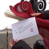 Des mains tiennent un rouleau de papier orné d'un ruban rouge et une carte disant « À François, de 254 414 signataires du Pacte pour la transition ».