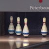 Cinq quilles sont debout dans une allée de bowling.