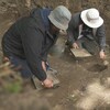 Deux archéologues fouillent dans le sol.