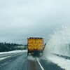 Un chasse-neige dégage une autoroute en projetant une gerbe de neige dans le fossé.