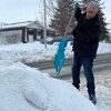 Un homme pique une pelle dans un banc de neige.