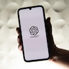 Une personne tient un téléphone affichant le logo de l'intelligence artificielle ChatGPT d'OpenAI.