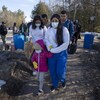 Une femme qui porte un masque chirurgical marche en tenant la main d'un enfant. D'autres personnes marchent derrière elle.