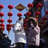 Deux femmes sous une enfilade de lanternes chinoises et une affiche où on peut lire « 2023 ».