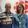 Christian Milot et Isabelle Castonguay dans les locaux de Radio-Canada. Ils portent tous les deux un foulard des scouts.