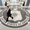 Un homme marche sur un plancher sur lequel on voit le logo de la CIA.
